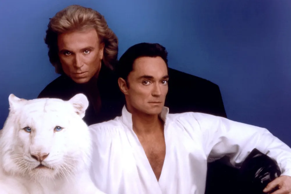 "Apresentação histórica da dupla mágica Siegfried e Roy com seus icônicos tigres brancos no palco do Mirage Hotel em Las Vegas"
